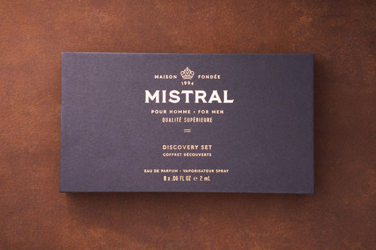 A dark blue box with gold text displays: MAISON FONDÉE 1994 MISTRAL POUR HOMME MEN'S COLOGNE QUALITÉ SUPÉRIEURE Mistral Eau de Parfum Discovery Set VAPORISATEUR SPRAY 8 x .06 FL OZ e 2 mL.