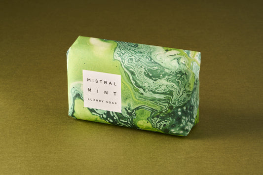 Mistral Marbles Mint Bar Soap on green surface; elegant marbled wrapping with “MISTRAL MINT” label, offering luxurious, lasting fragrance with garden mint and citrus notes.