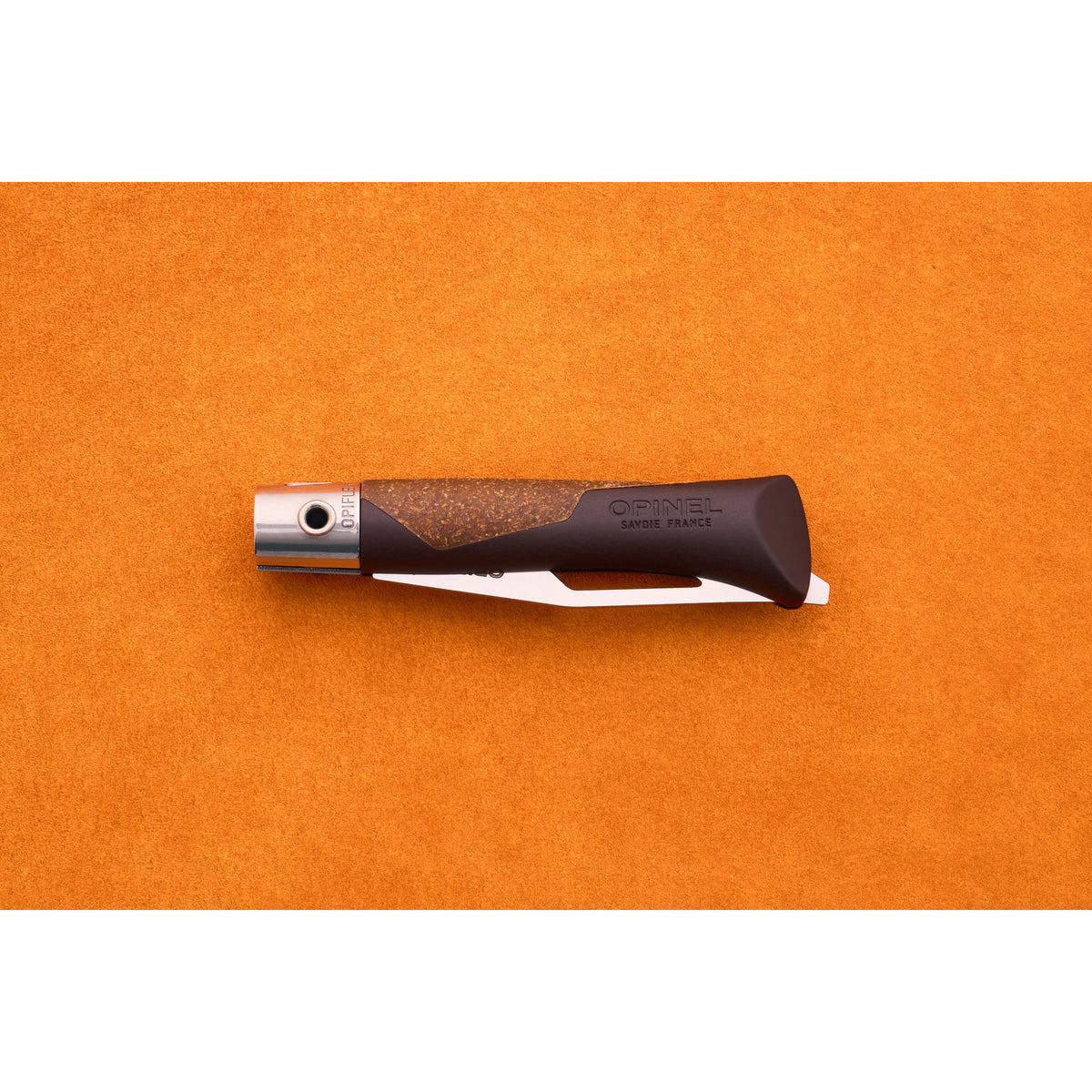 An Opinel Neo 7 Alpine pocket knife, closed with a dark handle and silver blade, rests on an orange textured background.