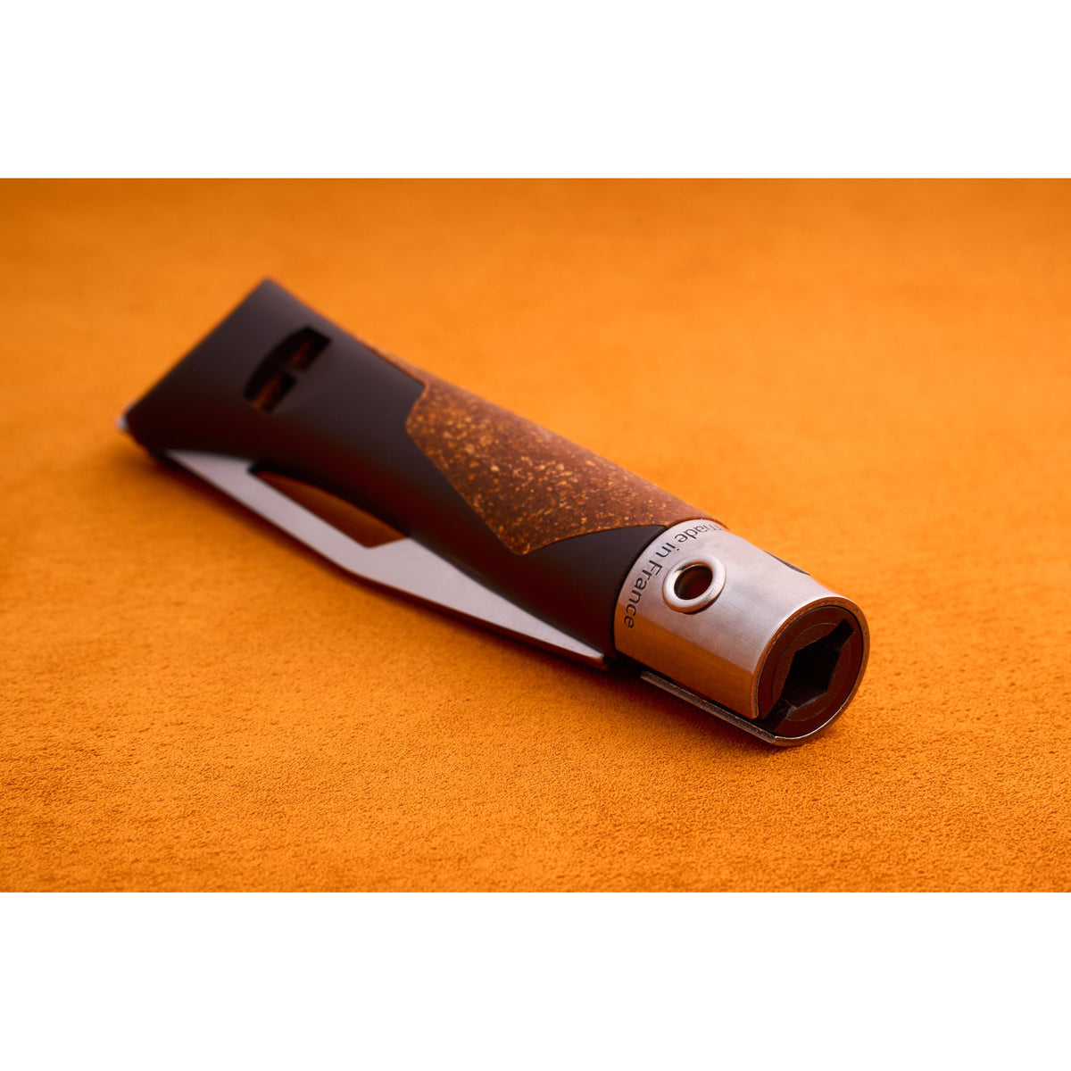 A close-up of the Opinel Neo 7 Alpine utility knife, featuring a modern metallic and brown design with a textured grip and serrated blade, resting on an orange surface.