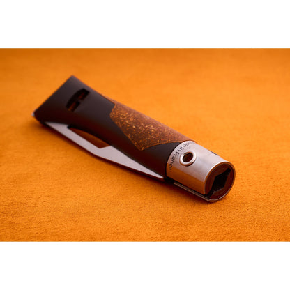 A close-up of the Opinel Neo 7 Alpine utility knife, featuring a modern metallic and brown design with a textured grip and serrated blade, resting on an orange surface.