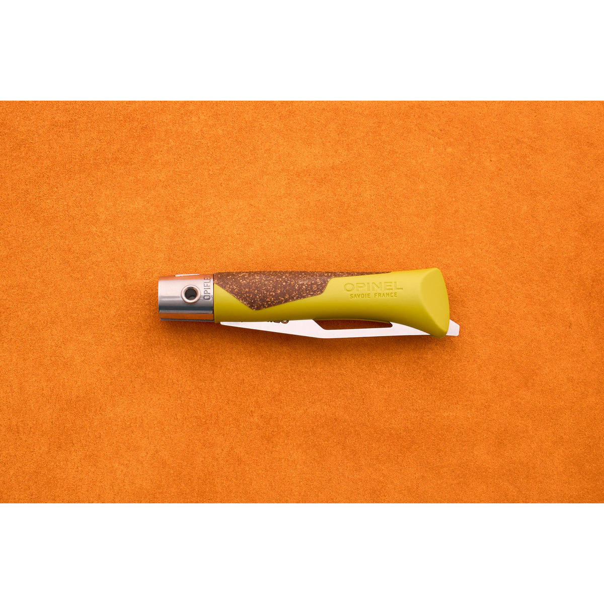 A closed Opinel Neo 7 Alpine pocket knife with a green and brown handle rests on an orange surface, displaying the Opinel Savoie France branding and embodying the practicality of a classic mountain tool.