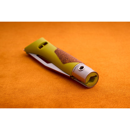 A close-up of the Opinel Neo 7 Alpine, a green and brown utility knife with a retractable blade designed as a versatile mountain tool, placed on an orange textured surface.