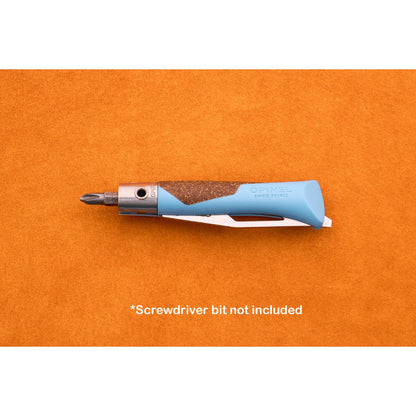 An Opinel Neo 7 Alpine knife, featuring blue and brown accents and designed as a versatile mountain tool, rests on an orange surface with a screwdriver bit attached. Text below reads *Screwdriver bit not included.