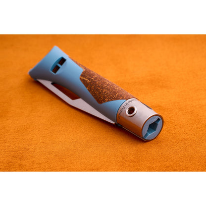 A blue and brown textured grip Opinel Neo 7 Alpine handle with a metal end rests on an orange surface. Reminiscent of a mountain tool, the handle features a hexagonal opening and engraved text near the metal part.