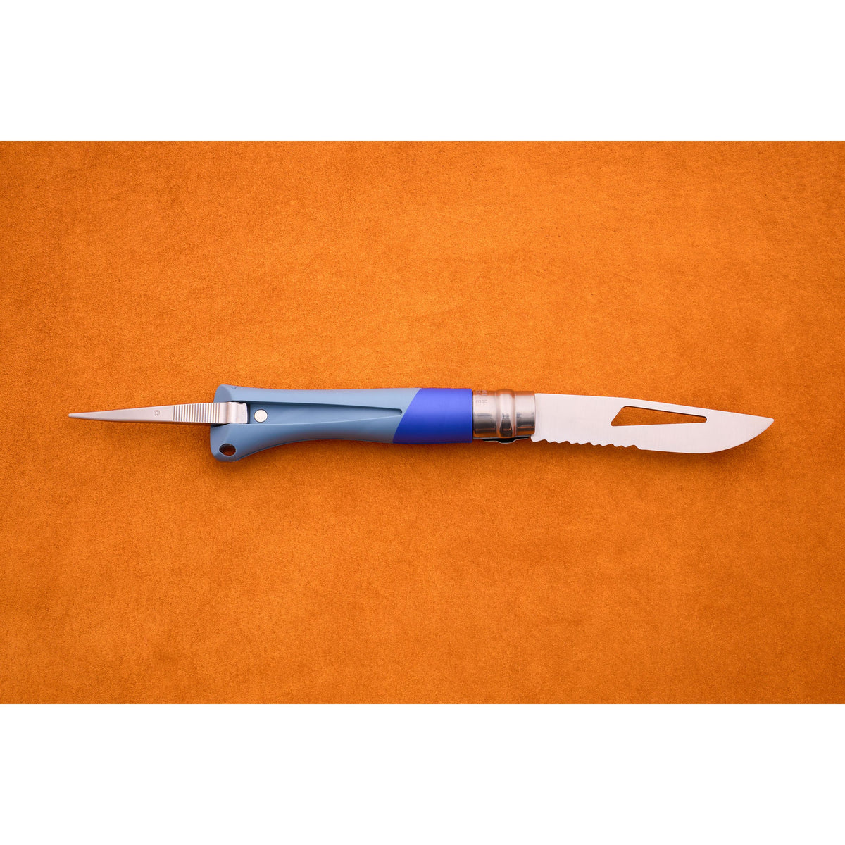 The Opinel No. 9 Ocean, featuring a blue handle, a pointed marlinespike on one end, and a partially serrated blade on the other, is displayed on an orange surface.
