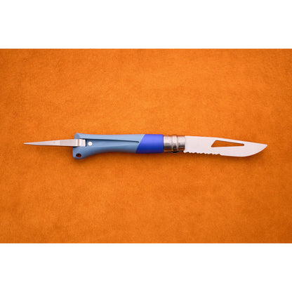 The Opinel No. 9 Ocean, featuring a blue handle, a pointed marlinespike on one end, and a partially serrated blade on the other, is displayed on an orange surface.