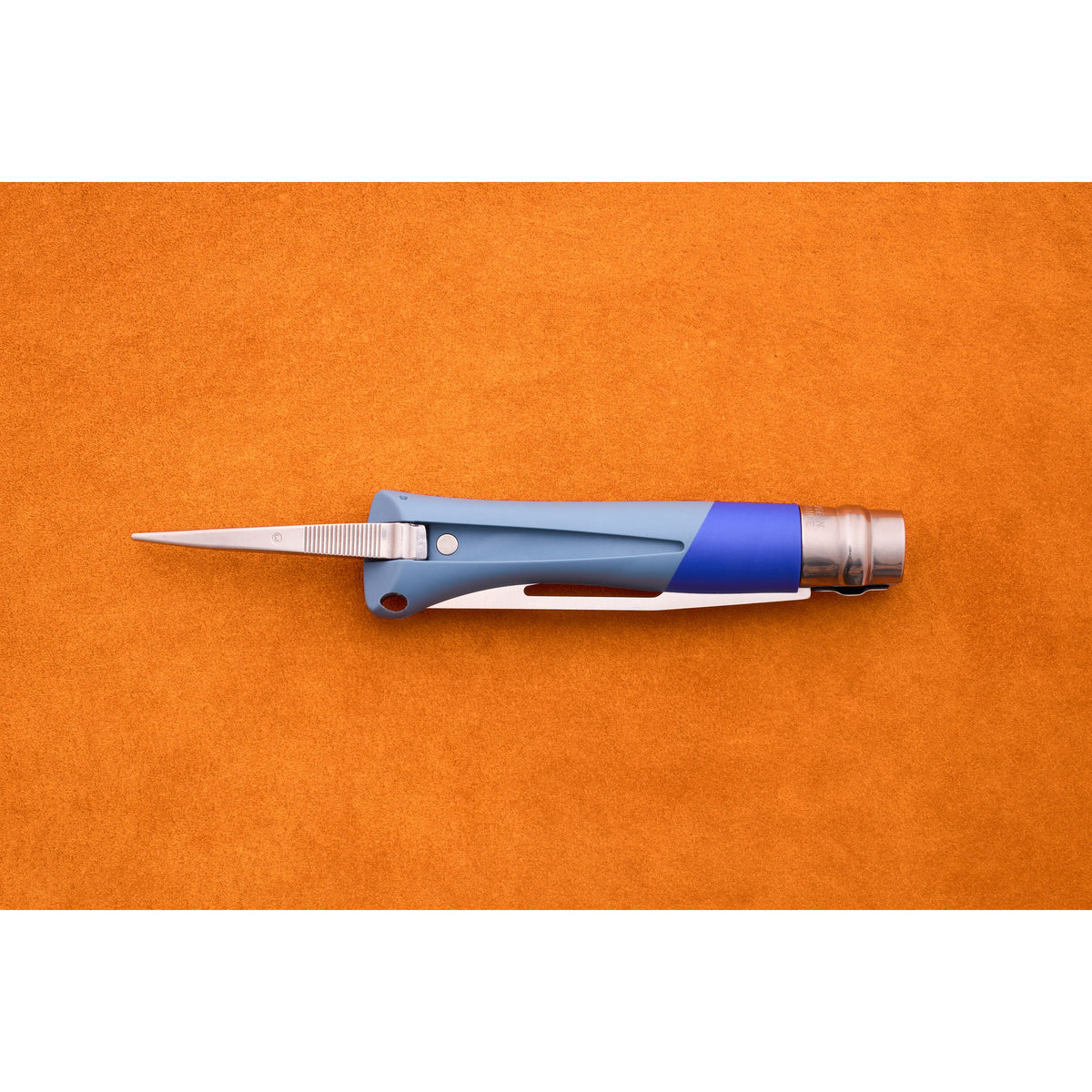 The Opinel No. 9 Ocean sailing knife, featuring a blue and silver design with its blade open, rests on an orange textured surface.