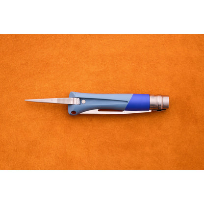 The Opinel No. 9 Ocean sailing knife, featuring a blue and silver design with its blade open, rests on an orange textured surface.