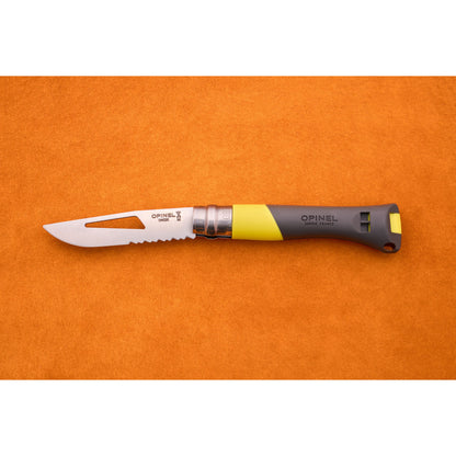 An Opinel No. 9 Ocean folding knife, featuring a partially serrated blade and a gray-yellow handle styled for sailing, is displayed on an orange surface.