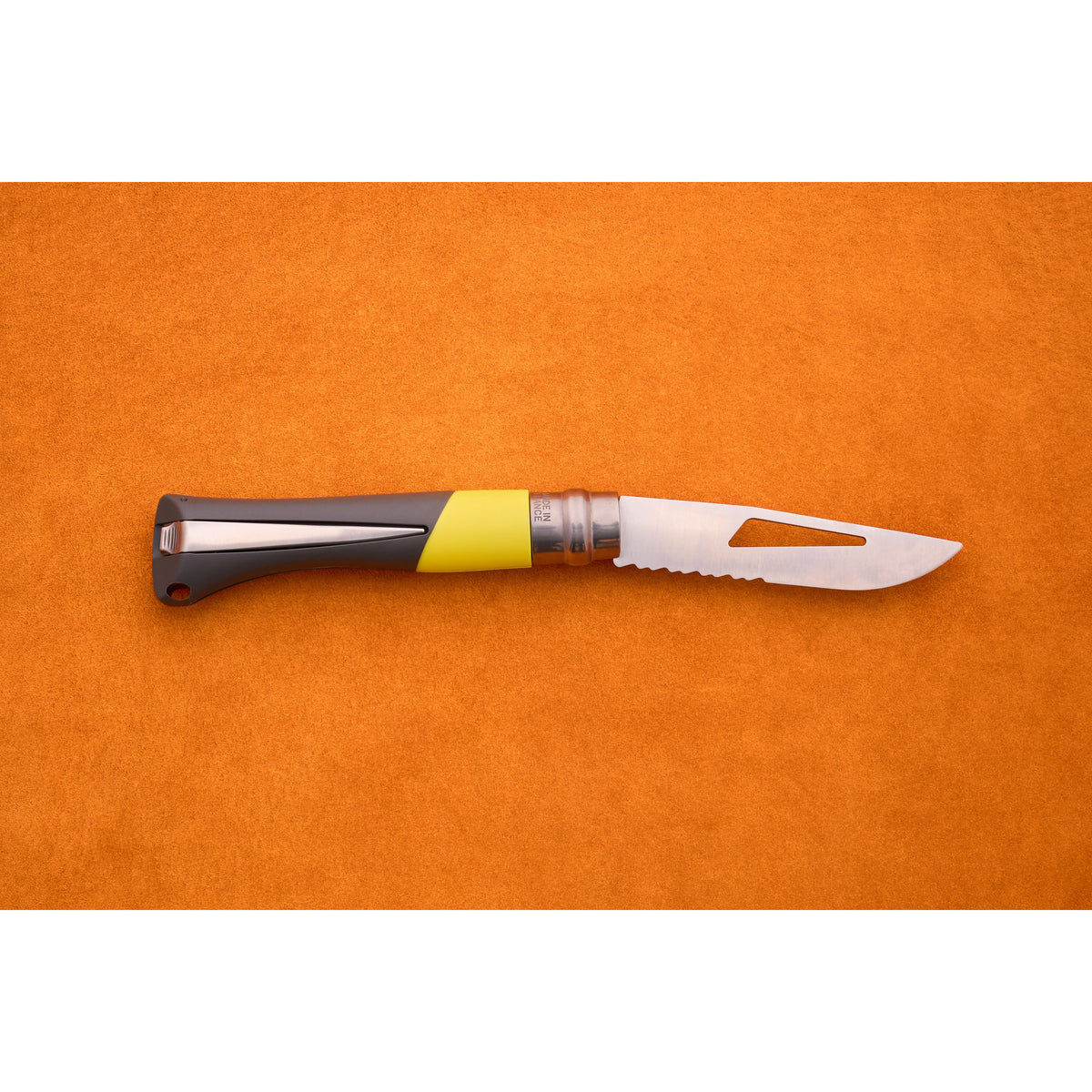 An Opinel No. 9 Ocean folding sailing knife with a gray and yellow handle and a partially serrated silver blade lies closed on an orange surface.