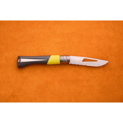 An Opinel No. 9 Ocean folding sailing knife with a gray and yellow handle and a partially serrated silver blade lies closed on an orange surface.