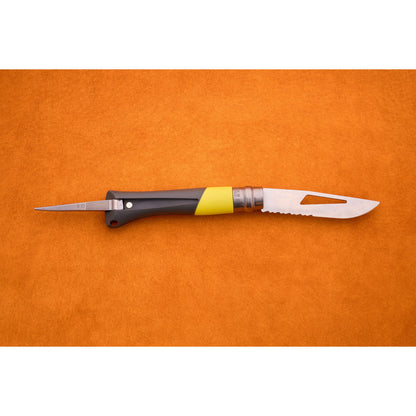 An Opinel No. 9 Ocean folding sailing knife with a black and yellow handle and a partially serrated blade lies open on an orange surface.
