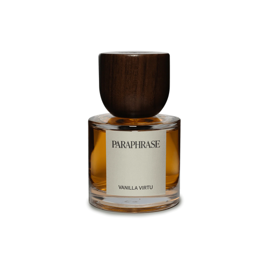 The Paraphrase Vanilla Virtu 50mL Eau de Parfum—a clear glass bottle filled with amber liquid, labeled "PARAPHRASE" with "VANILLA VIRTU" below, and topped by a dark wooden cap—stands elegantly on a white background. This creation comes from an independent perfume house devoted to hand-blended, cruelty-free fragrances.