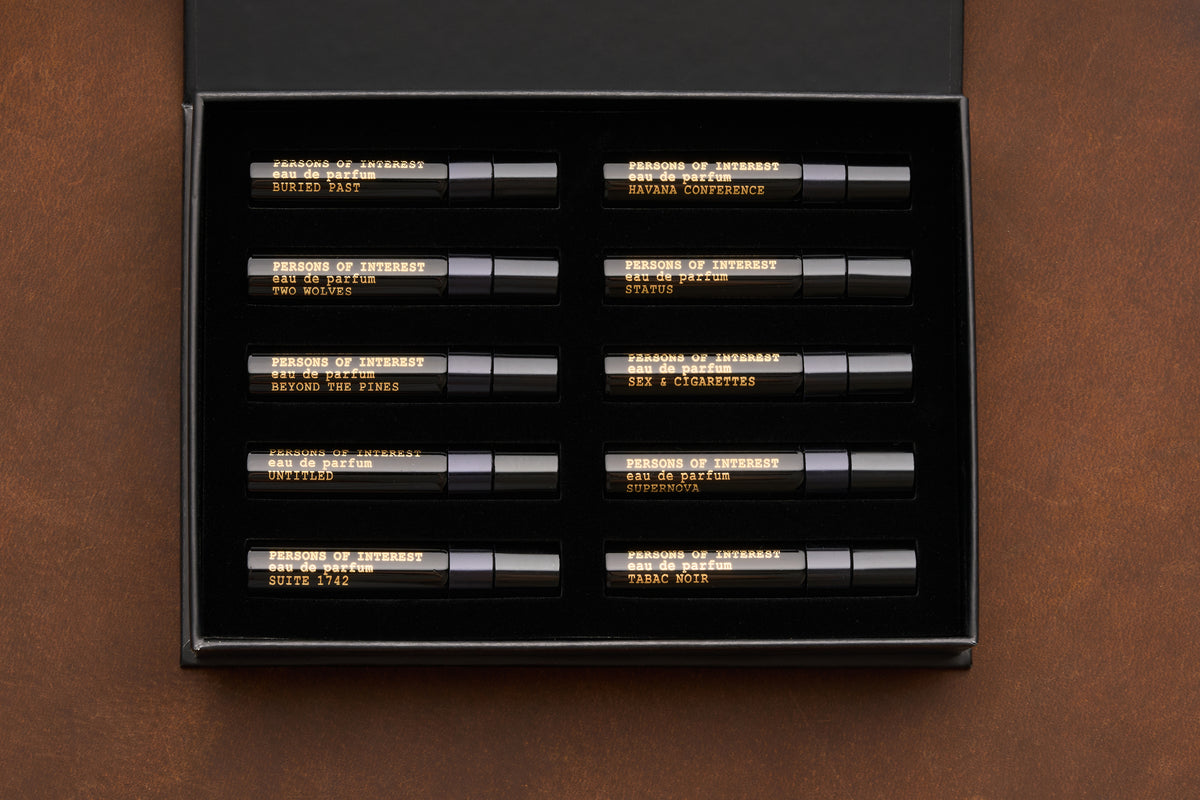The Persons of Interest Eau de Parfum Discovery Kit features ten unisex 5ml fragrances, each housed in a sleek black box with gold-labeled vials fitted into individual slots. This curated set includes scents like STRANGE PARADISE, STATIC, SEX + CIGARETTES, and more.