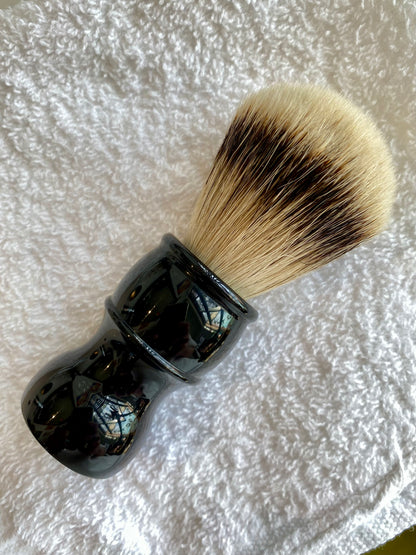 Nolan's All-In-One Shaving Kit featuring a traditional shaving brush with dense bristles and a glossy black handle rests on a white towel.