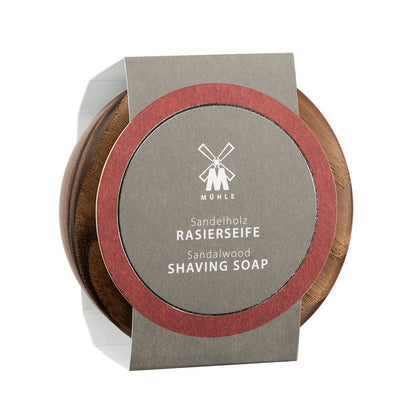 A wooden bowl holds Mühle Sandalwood Shaving Soap, which features a gray and red label displaying the product name in both German and English. Known for its luxurious sandalwood scent and exceptional lather, Mühle Sandalwood Shaving Soap is an ideal option for those looking for a classic, traditional shaving soap experience.