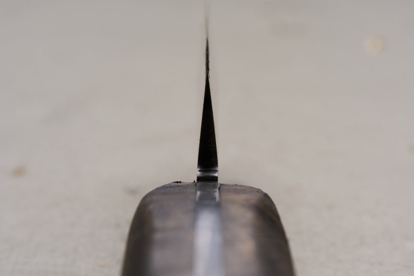 Close-up view of the RESQ Knives Korpi Camp Kitchen Knife from the handle, highlighting its thin, sharp edge crafted from recycled stainless steel, with a softly blurred background.