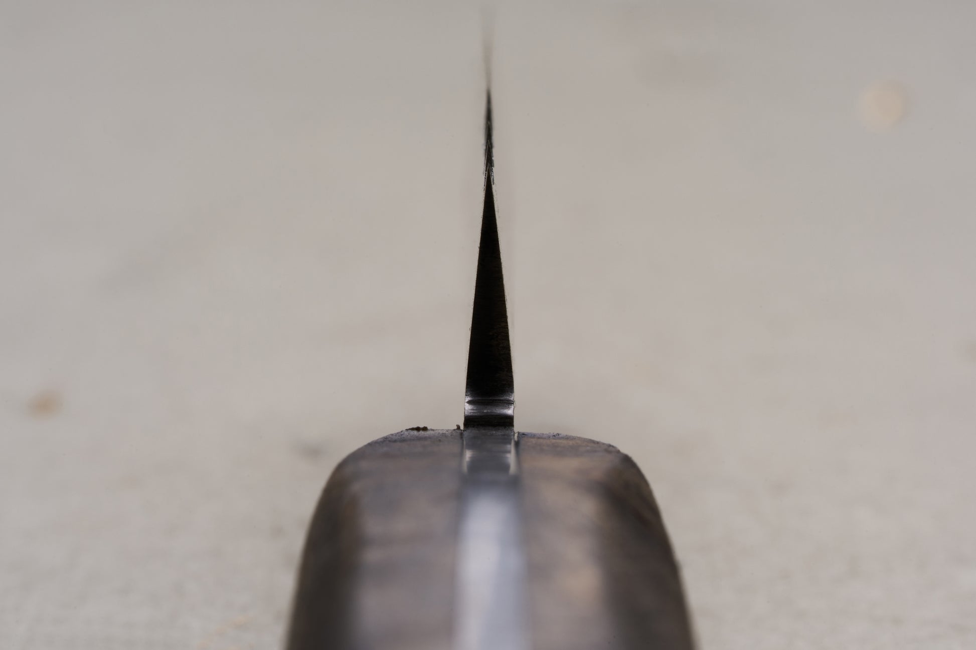 Close-up view of the RESQ Knives Korpi Camp Kitchen Knife from the handle, highlighting its thin, sharp edge crafted from recycled stainless steel, with a softly blurred background.