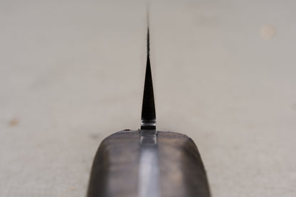 Close-up view of the RESQ Knives Korpi Camp Kitchen Knife from the handle, highlighting its thin, sharp edge crafted from recycled stainless steel, with a softly blurred background.