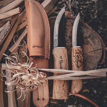Roselli Hunter/Carpenter Knife Combo Sheath features two birch-handled carving knives, leather sheath, and wood shavings on a log slice, ideal for bushcraft enthusiasts.