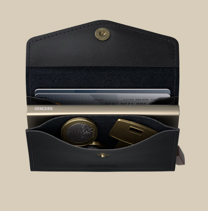 An open black Secrid Envelope Wallet, set against a beige background, contains a card, coins, a gold RFID-blocking wallet labeled SECRID, and a gold key-shaped item.