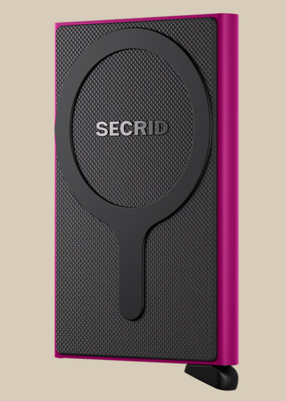 A slim, rectangular Secrid Wallets Cardprotector for MagSafe with a textured black front, circular MagSafe-compatible design, RFID blocking, and vibrant pink edges stands on a small black tab against a beige background.