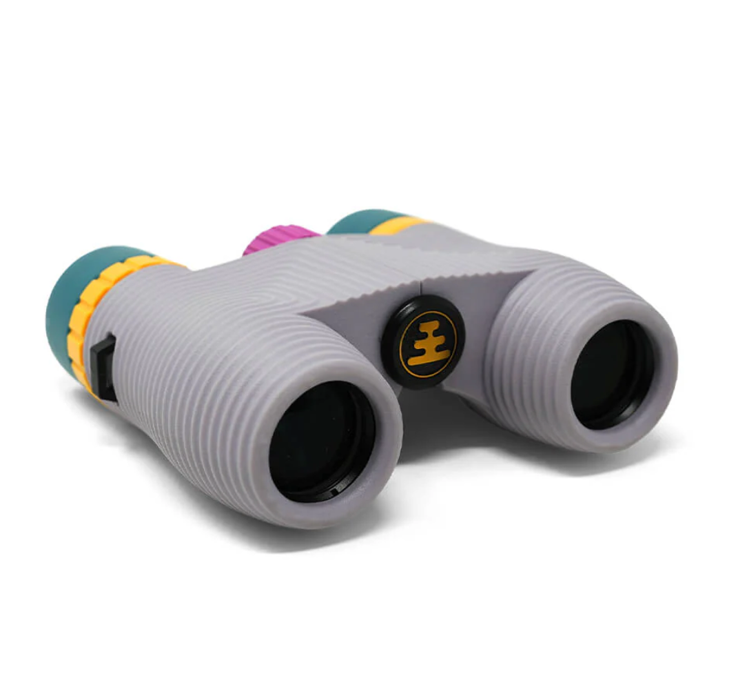 NOCS Provisions Standard Issue 8x25 Waterproof Binoculars, featuring ribbed housing, unique colored accents, and compact design for effortless handling, ideal for adventurous explorations.