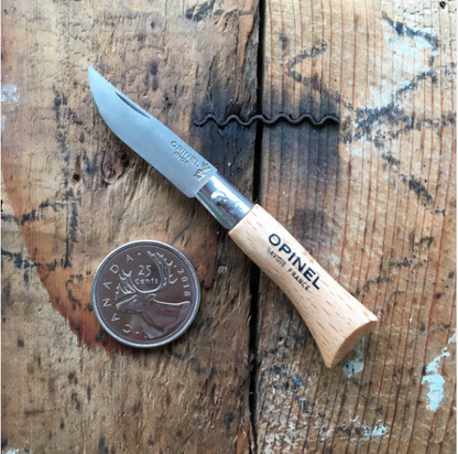 Opinel Inox No.02 Folding Knife with light wooden handle, open blade, and 2018 Canadian quarter for scale, on a worn wooden surface.