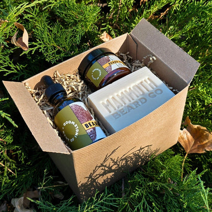 Kent of Inglewood Forest Beard Box with beard oil, balm, and Mammoth Beard Co. cedarwood soap, nestled in greenery, ideal for grooming enthusiasts.