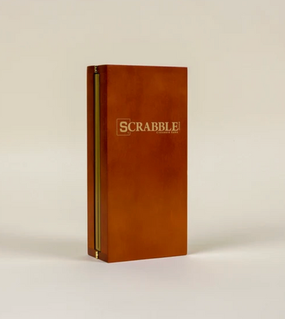 A folding wood case for the Scrabble Deluxe Travel Edition Board Game standing upright and closed, featuring the game logo on the front.