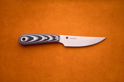A Spyderco Bow River fixed-blade hunting knife, featuring a black and gray patterned handle and a shiny curved stainless steel blade, lies flat on an orange surface.