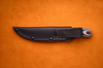 A Spyderco Bow River knife in a black sheath with a loop rests on an orange textured surface, with part of the handle showing.
