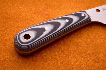 Close-up of the Spyderco Bow River handle featuring layered black and gray patterns and three rivets, displayed on an orange textured surface.