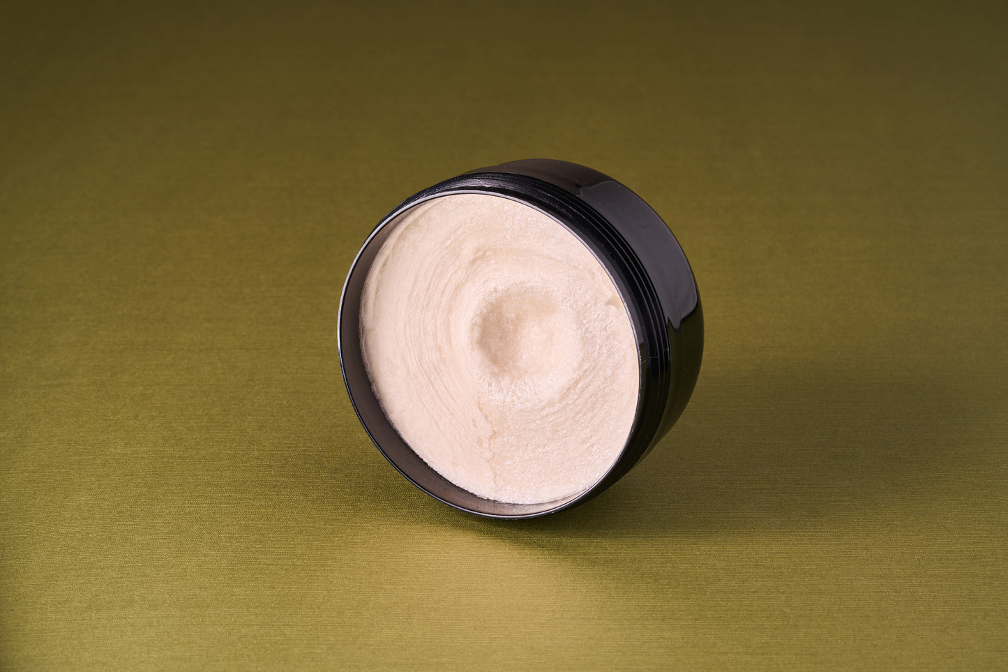 Taylor of Old Bond Street Tobacco Leaf Shaving Cream in an open black jar, showcasing its rich, off-white whipped texture, ideal for a luxurious shaving experience.