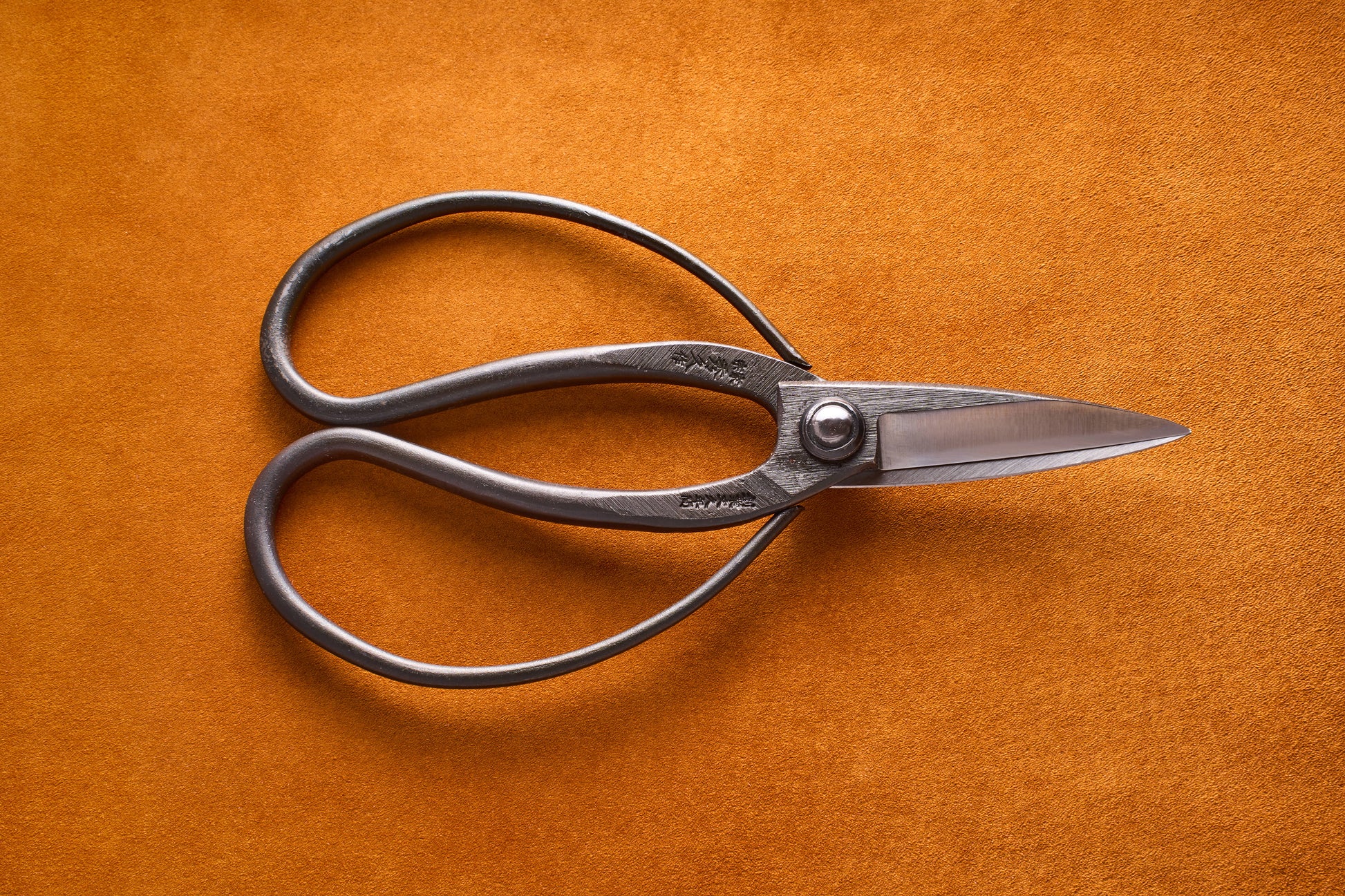 Pair of silver scissors on a brown leather surface