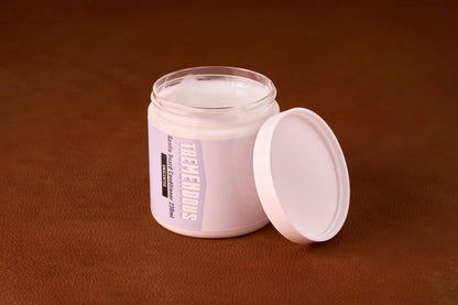 TREMENDOUS Beard Conditioner jar open on leather surface, showcasing creamy texture. Unscented formula with Argan Oil, ideal for silky, volumized beard care. 230 ml.