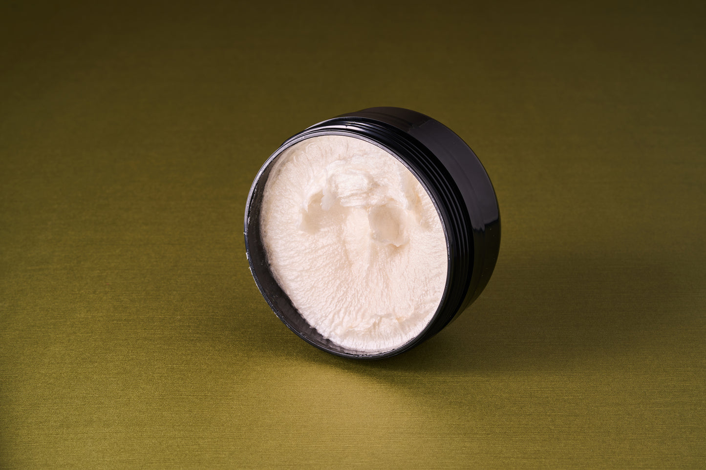 Truefitt & Hill Sandalwood Shave Cream in an open black jar, showcasing its rich, white texture ideal for a protective, classic shave experience.