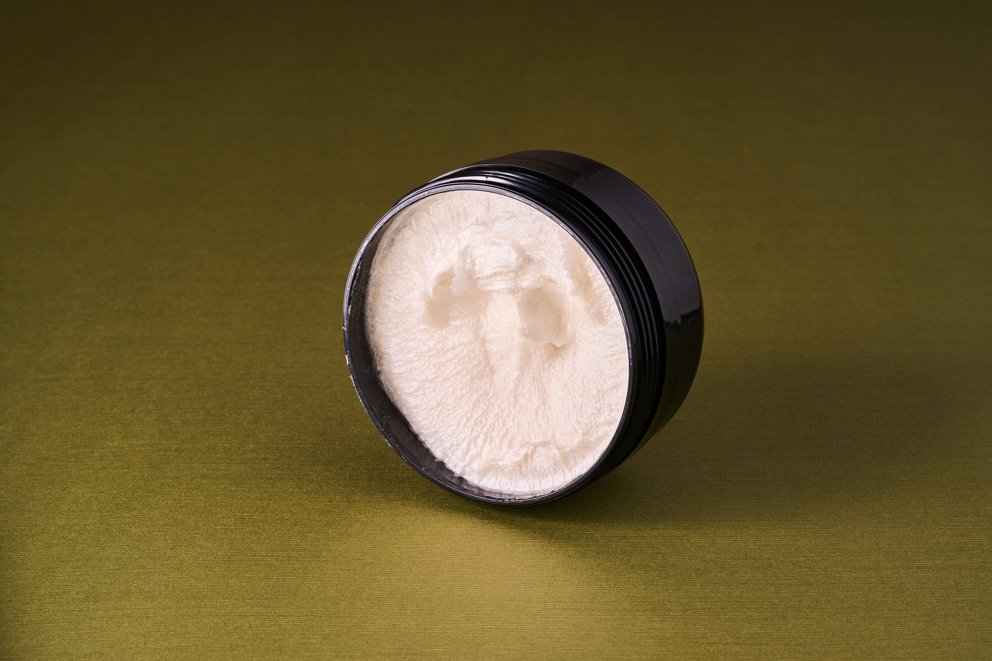 Truefitt & Hill Sandalwood Shave Cream in an open black jar, showcasing its rich, white texture ideal for a protective, classic shave experience.