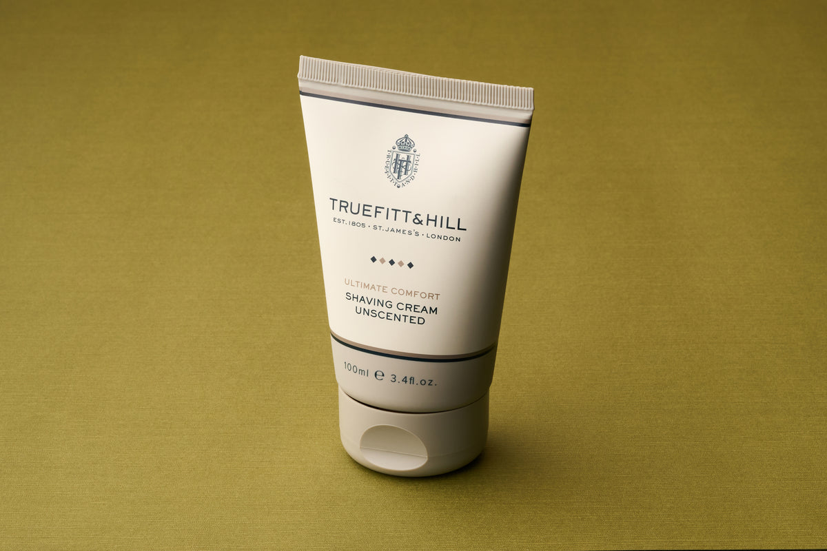 A 100ml tube of Truefitt & Hill Ultimate Comfort Shave Cream stands upright against a plain olive-green background—perfect for anyone desiring a sophisticated Victorian-style shave paired with modern-day comfort.