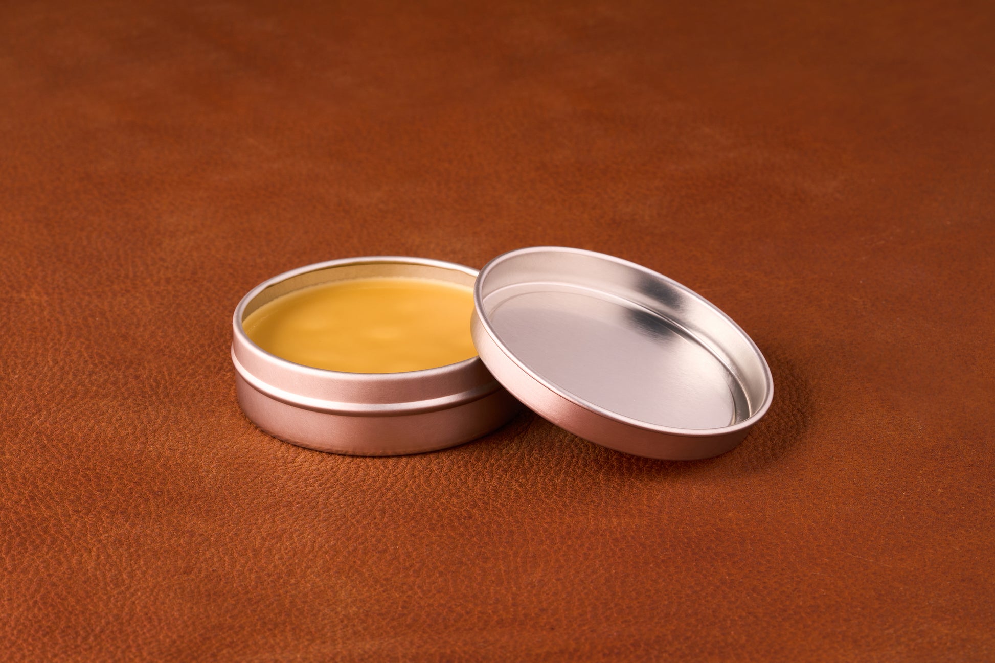 Uncle Normans Moustache Wax Tamer, in a metal tin on leather, showcases smooth yellow balm, ideal for versatile styling with pine-sap smoothness and impressive long-lasting hold.