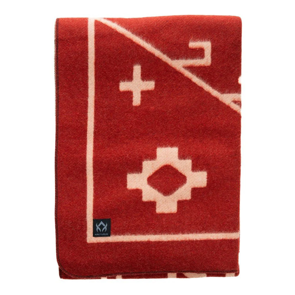 The Arcturus Rainier Wool Blanket is a folded red wool blanket featuring cream geometric patterns and a small black logo patch in the bottom corner, perfect for cozying up while camping or adding to your collection of wool blankets.