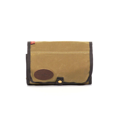 Frost River Roll Up Travel Kit in waxed canvas with brass button, ideal for organizing toiletries or tools; features multiple pockets and a hanging loop.