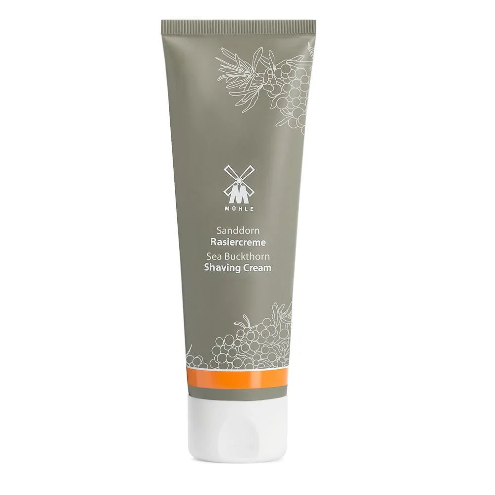 A gray tube of Mühle Sea Buckthorn Shaving Cream, labeled in German and English, is enriched with natural essential oils and adorned with delicate white floral designs and orange accents. The Mühle Sea Buckthorn Shaving Cream stands upright against a pristine white background.