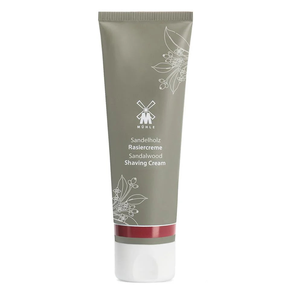A tube of Mühle Sandalwood Shaving Cream, featuring a gray body, white cap, floral design, and white product details, provides a luxurious natural shaving cream experience.