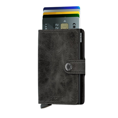 Secrid Wallets Miniwallet - Vintage: Grayish-black leather wallet with snap closure and lever for easy card access, featuring multiple colorful cards and RFID blocking.