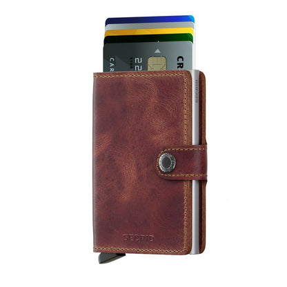 Secrid Wallets Miniwallet - Vintage, a brown leather wallet with metal card-protector, fanned credit cards, and secure front clasp, embodying style and function.