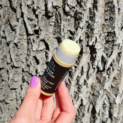 Hand holding Boreal Folk Tallow Skin Stick, a natural balm in eco-friendly packaging, ideal for nourishing skin with cocoa butter and tallow.