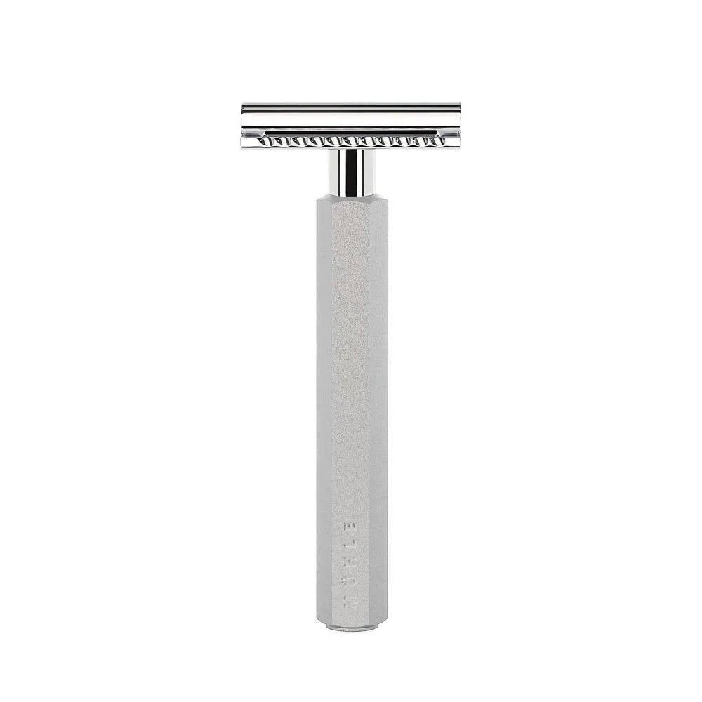 The Mühle Hexagon Safety Razor, featuring a textured, anodised silver aluminum handle and a polished metal head, stands upright against a white background—blending contemporary design with traditional shave culture.