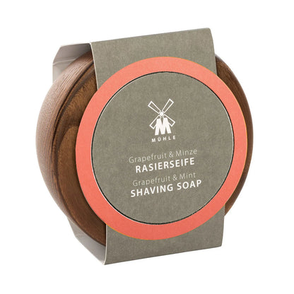 A round wooden container with a gray and orange label displays the product name “Mühle Grapefruit & Mint Shaving Soap” in both English and German. This vegan shaving soap offers a refreshing blend of grapefruit and mint scents, while the lid is adorned with Mühle’s signature windmill logo.